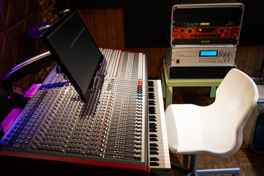 audio mixing console, blank white chair and sound processing equipment in recording studio
