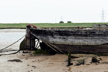 Fototapeta na wymiar Oare, Faversham, Kent, UK. Derelict boat at low tide.