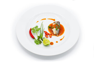 Sardine piece in tomato sauce decorated by chili ,spring onion , pepper , coriander and lemon in the white plate.