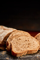 Freshly made integral black domestic bread on black stone cutting board. Very shallow depth of field