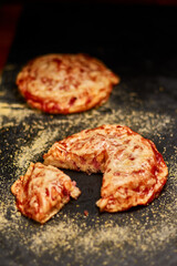 Freshly made pastry with ham, cheese and tomato sauce on black stone cutting board. Very shallow depth of field