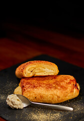 Freshly made rolled bun with fresh cheese on black stone cutting board, sprinkled with corn flour. Very shallow depth of field