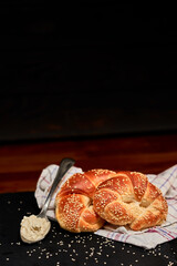 Freshly made rolled bun with fresh cheese on black stone cutting board, sprinkled with sesame seeds. Very shallow depth of field