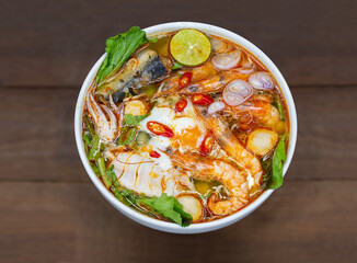 Tom Yum Kung is spicy shrimp boiled in the white bowl with fresh vegetable and spicy ingredients.