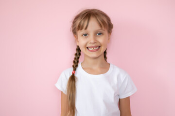 Pretty little girl in a white t-shirt smiling on a pink background