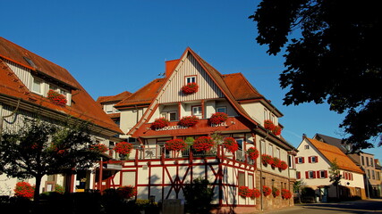 Schöner Gasthof im Schwarzwald geschmückt mit vielen roten Blumen unter blauem Himmel