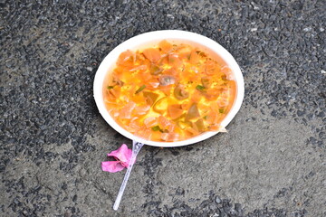 Food plate thrown in road wasted food found rain water on plate.