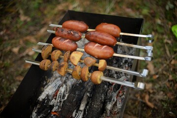 barbecue with coals, pork skewers and potatoes on skewers