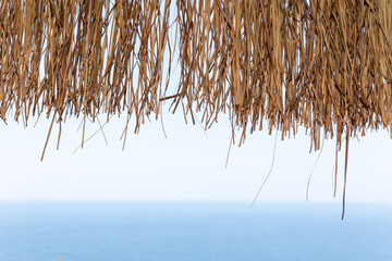 Texture of dry straw on the roof of view with a blue sea background. holiday background.