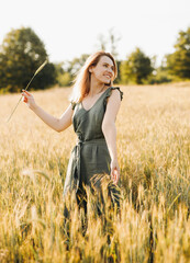 Gorgeous blonde holding a spikelet of wheat at sunset.