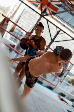 Training in the gym in the ring with a muay thai trainer. Tattooed caucasian man and Asian trainer. Muay thai training.