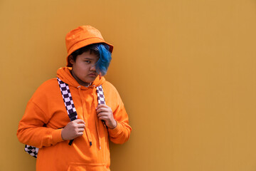 Back to school. Teenage girl with blue hair in an orange hoodie, a Panama hat with a backpack. High school kid.Education.