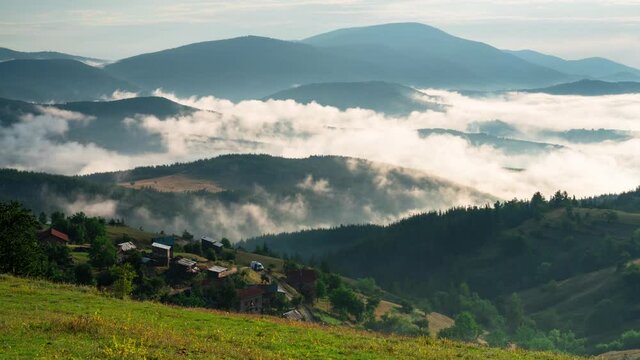 Time lapse with playful, fast-moving morning mists over the tree-covered mountain slopes and the villages nestled in them, Rhodope mountains in Bulgaria