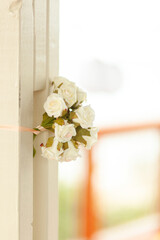 Small white roses bouquet as a design element for a wedding decoration on a white wooden fence of a terrace in an open air restaurant