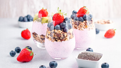 Superfoods layered pudding with granola, blueberry and strawberry in glasses. Yogurt with chia seeds, berries, kiwi and muesli for healthy breakfast, copy space. Perfect for summer snack or dessert