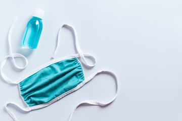 Protective face mask and hand sanitizer gel on white background, top view, copy space. New normal...