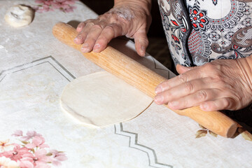 A woman rolls out the dough with a rolling pin