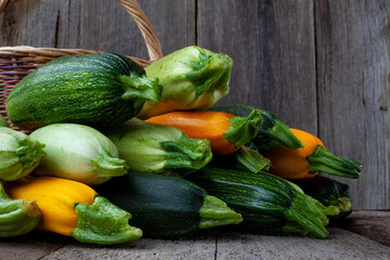 A set of multi-colored zucchini yellow, green, white, orange on the table close-up. Food background. Fresh harvested courgette, cropped summer squash. Picked green courgettes. Still life in kitchen.