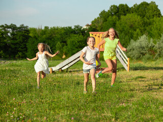 Fototapeta premium Kids, children running on meadow in summer's sunlight. Look happy, cheerful with sincere bright emotions. Cute caucasian boys and girls. Concept of childhood, happiness, movement, family and summer.