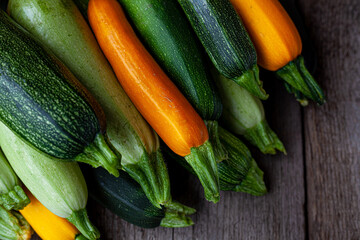 A set of multi-colored zucchini yellow, green, white, orange on the table close-up. Food background. Fresh harvested courgette, cropped summer squash. Picked green courgettes. Still life in kitchen.