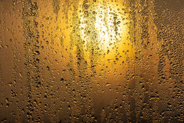 Drops of water on a glass window at dawn as an abstract background.