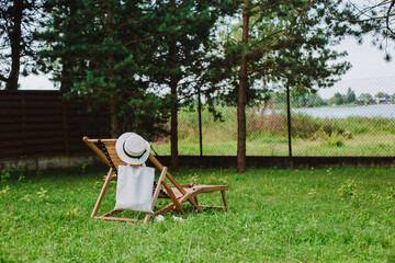 Cotton wicker hat and eco bag near wooden deck chair