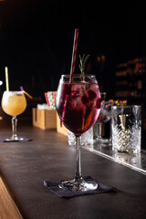 Two alcoholic cocktails pink and yellow on a dark bar.
