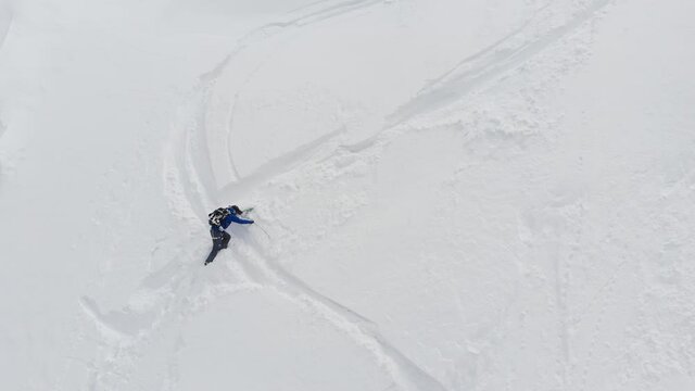 An aerial view of a male athlete athlete skier clambering up a steep slope up. Skitour freeride backcountry climbing with skis through the snow high in the mountains of the North Caucasus