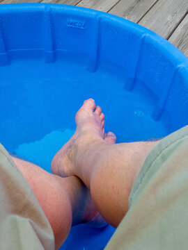 man's feet submerged in blue kiddie pool