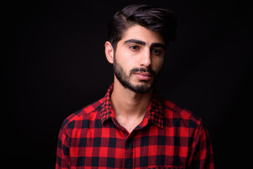 Young handsome bearded Persian man against black background
