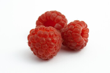 Three ripe raspberries isolated on a white background close-up. Fresh raspberries without sheets on the table. Macro shooting. Healthy and wholesome food concept