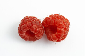 Two ripe raspberries isolated on a white background close-up. Fresh raspberries without sheets on the table. Macro shooting. Healthy, wholesome food. Top view.