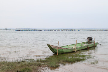 Obraz premium Scenery of old local fishery boat in the lake with natural background in rainy day. 