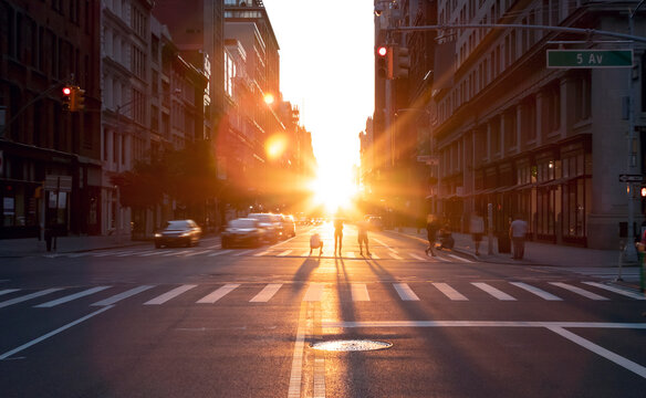 People standing in the middle of the intersection at 23rd Street in New York City taking pictures of the summer sunset