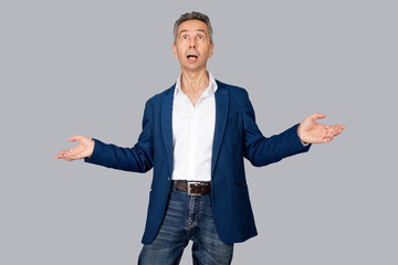 Attractive man is holding opened palms. Man shows gesture of surprise. Isolated grey background