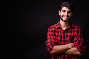 Young handsome bearded Persian man against black background