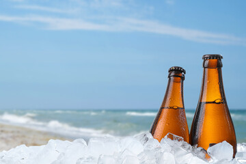 Bottles of beer and ice cubes against blurred sea. Space for text