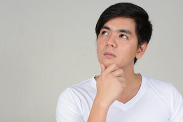 Obraz premium Portrait of young handsome Asian man against white background