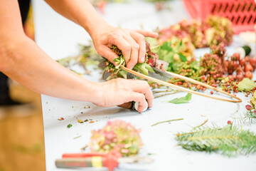 Florist at work: woman making rose hip and hawthorn wreath