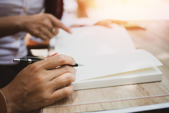 Asian young man and woman sitting pointing studying examining, Tutor books with friends Young students campus helps friend catching up and learning. People learning education