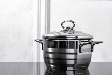 Aluminum cookware on black induction stove against grey wall
