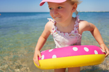 Little girl in bikini swimming in sea with swimming circle