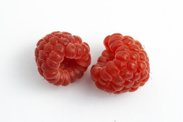 Two ripe raspberries isolated on a white background close-up. Fresh raspberries without sheets on the table. Macro shooting. Healthy, wholesome food. Top view.