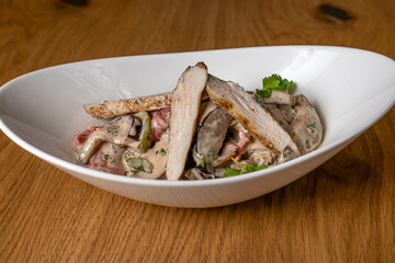 Warm salad with meat slicing in a white plate. Restaurant dishes. Meat salad, not vegans, chicken