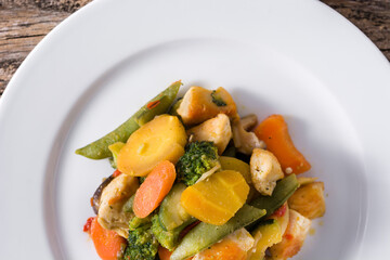 Stir fry chicken with vegetables on wooden table. Top view