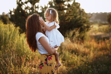 Mom and daughter happy together and play on a walk in the summer