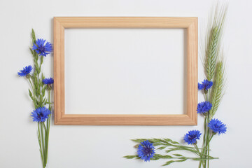 blue cornflowers and cereals with wooden frame on white background