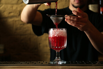 Bartender preparing fresh alcoholic cocktail at bar counter, closeup