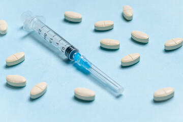 Syringe with pills on blue background