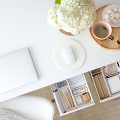 The gold stationery is neatly arranged in white containers in the drawers of the nightstand. Storage and tidying up the workplace.